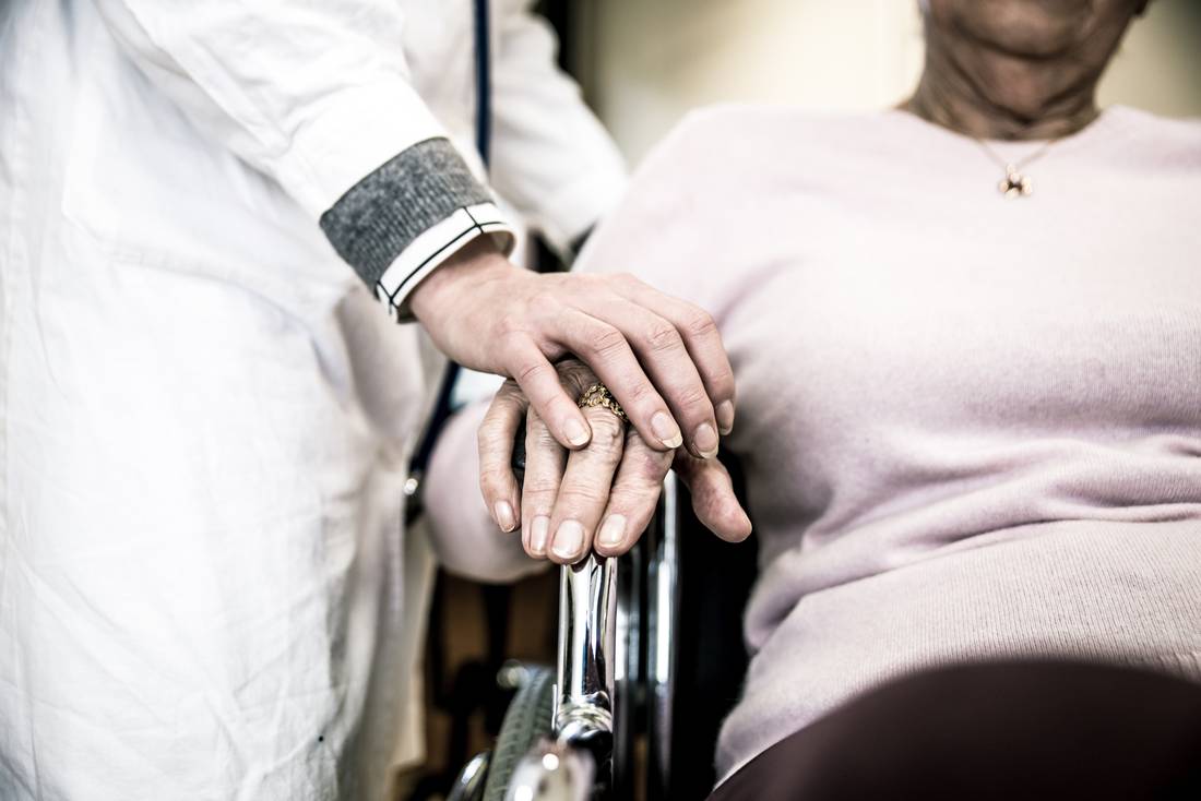 A caregiver's hand resting on the hand of an older resident